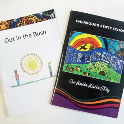 Two Indigenous story books fanned out on a white desktop. One is titled Out in the Bush, the other is For Our Elders.